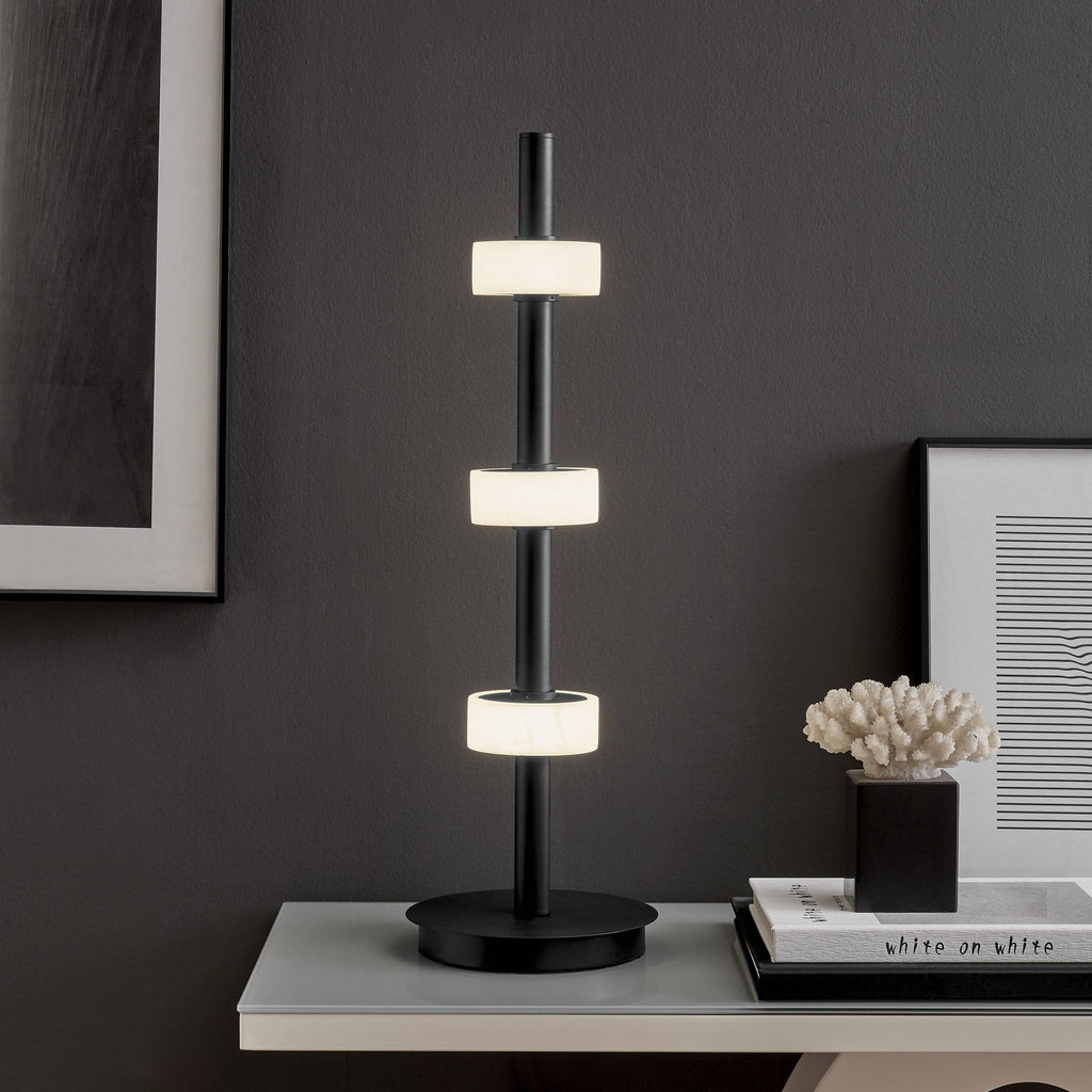 Black table lamp with alabaster LED rings and adjustable light temperature for modern spaces.